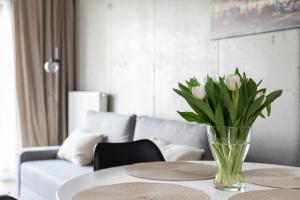 a vase of white flowers on a table in a living room at River Side Apartments in Oświęcim