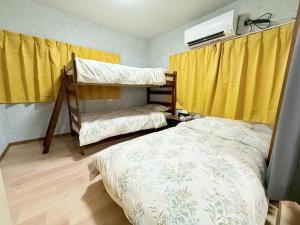 a bedroom with two bunk beds and yellow curtains at Okayama Urban Peach in Okayama