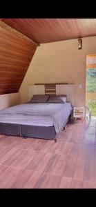 ein großes Bett in einem Schlafzimmer mit Holzboden in der Unterkunft Chalé Belém in Eldorado