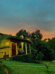a yellow house with a bench in front of it at Chalé eldorado in Capela Ivapurunduva