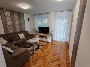 a living room with a couch and a tv at Beta Apartman in Bük