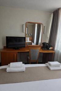a bedroom with a desk with a television and a mirror at Hotel Bellevue in Skopje