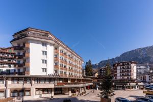 a large white building with mountains in the background at Hotel Alaska Cortina in Cortina dʼAmpezzo
