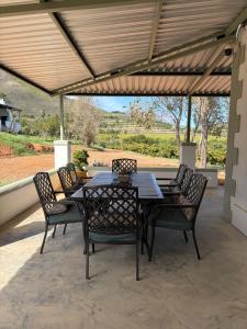 a table and chairs on a patio with a roof at Windkraal Farm Studio in Bonnievale