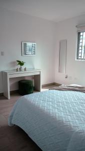 a white bedroom with a bed and a desk at Ankara Residence in Santo Domingo