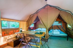 a tent with a table and chairs and a bed at Huttopia Les Deux Lacs - Laurentides in Saint-Faustin