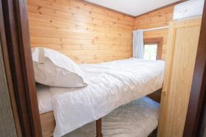 a small bedroom with a bed in a wooden wall at Neaum Crag Lodge ideal for a couple or family with young children in a woodland setting at Skelwith Bridge in Grasmere +8 photos
