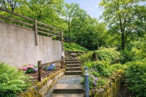 a stone wall with stairs in a garden at Neaum Crag Lodge ideal for a couple or family with young children in a woodland setting at Skelwith Bridge in Grasmere