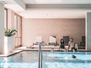 a group of people sitting in a swimming pool at Falkensteiner Hotel Cristallo l 4 Star Superior in Katschberghöhe