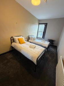 two beds in a small room with a window at The Victoria Bar & Hotel in Wakefield