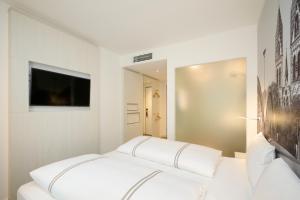 a white room with a bed and a tv at Premier Inn Freiburg City Nord in Freiburg im Breisgau