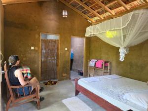 a woman sitting in a chair in a bedroom with a bed at The Mud House in Talalla South