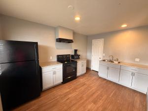 a kitchen with a black refrigerator and white cabinets at Super 8 by Wyndham Sonora in Sonora