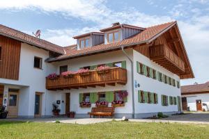 a white building with a balcony and a bench at Bauernhaus Markus Köpf in Füssen