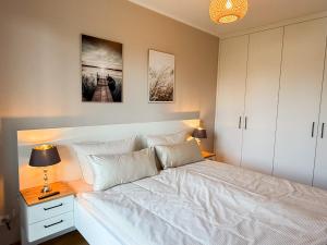 a bedroom with a white bed and a night stand with a lamp at Ferienwohnung Gartenidyll am Dümmer See in Lembruch