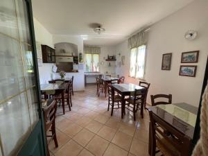 a dining room with tables and chairs and a kitchen at Agriturismo Valle Martina in Saturnia