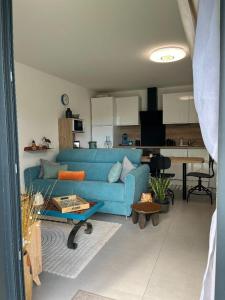 a living room with a blue couch and a kitchen at Casanella in Le Hézo