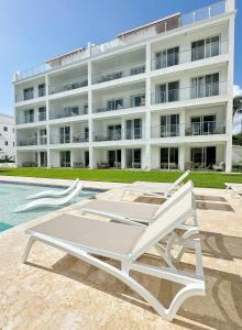 a white chaise lounge next to a large building at Mananero III in Sosúa