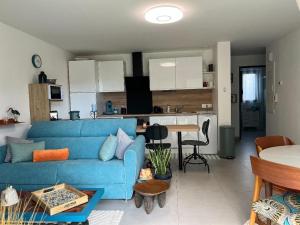 a living room with a blue couch and a kitchen at Casanella in Le Hézo