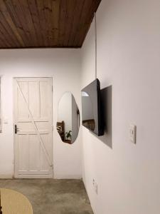 a room with a white wall with a mirror and a door at Casinha Verde, Itacaré in Itacaré