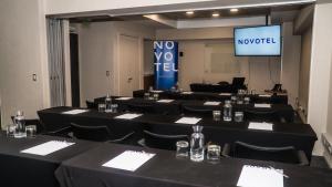 a conference room with black tables and chairs and a screen at Novotel Puerto Montt in Puerto Montt