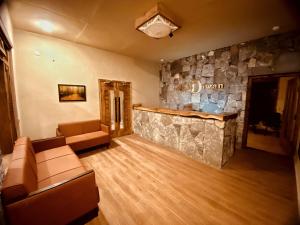 a lobby with a stone wall and couches and a bar at Diwan-e-Hunza Resort in Gulmit
