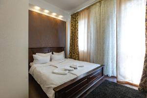 a bedroom with a bed with white sheets and a window at HARMONY Apart in Truskavets