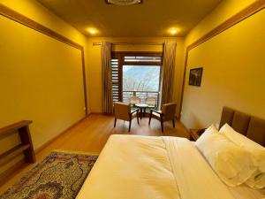 a bedroom with a bed and a table in it at Diwan-e-Hunza Resort in Gulmit