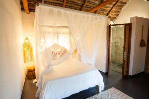 a bedroom with a white bed with a canopy at Tofo Beach Gardens in Inhambane
