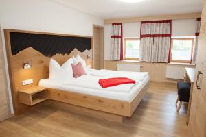 a bedroom with a large white bed with red pillows at Bauernhaus Markus Köpf in Füssen