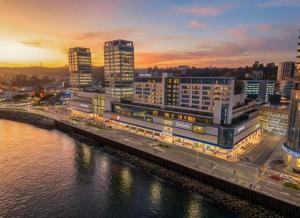 a city with tall buildings next to a river at Novotel Puerto Montt in Puerto Montt