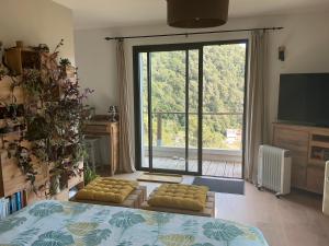 a living room with a large window and a tv at Chambres d hôtes les Romarins in Cantaron