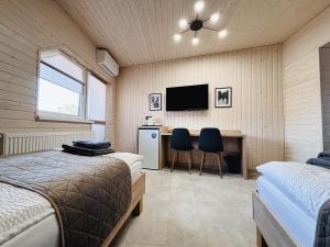 a bedroom with two beds and a desk with a television at Old Friend Guest House in Berehove