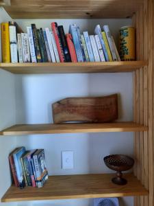 a book shelf filled with lots of books at Mountain view Bespoke tiny home in Plettenberg Bay