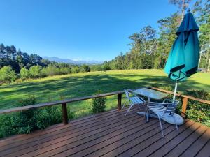 a table and an umbrella on a wooden deck at Mountain view Bespoke tiny home in Plettenberg Bay
