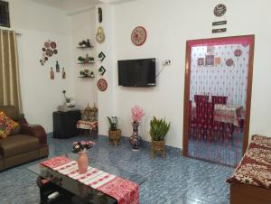 a living room with a couch and a tv on the wall at Bhanu Homestay in Nowgong