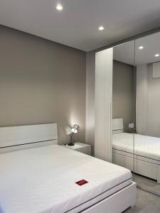 a bedroom with a large white bed and a mirror at Casa di WR in Imperia