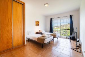 a bedroom with a bed and a couch and a window at GuestReady - Casa das Estrelas in Estreito da Calheta