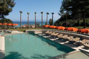 a swimming pool with lounge chairs and umbrellas at Zeus Eleva Kassandra Lagoon in Hanioti