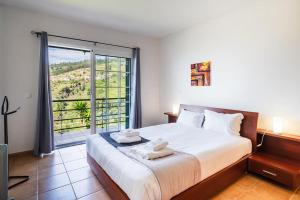 a bedroom with a large bed and a large window at GuestReady - Casa das Estrelas in Estreito da Calheta