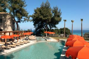a swimming pool with orange umbrellas and chairs at Zeus Eleva Kassandra Lagoon in Hanioti