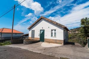 a small white house with a green door at GuestReady - Casa das Estrelas in Estreito da Calheta