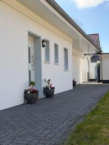 a white house with two pots of flowers next to it at Ferienhaus Pirat Störtebeker Dangast in Dangast