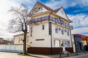 a white building with a tree in front of it at Villa Royal in Craiova