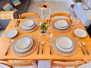 a wooden table topped with white plates and silverware at Fibonacci Beachfront Apartment in Flic-en-Flac