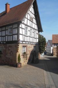 an old black and white building on a cobblestone street at Ferienhaus Pfalzklause in Billigheim-Ingenheim