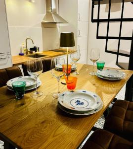 a wooden table with wine glasses and plates on it at Refugium Lodziense II - Quiet luxury in the center of Lodz in Łódź