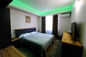 a bedroom with a bed and a desk and green lights at Villa Royal in Craiova
