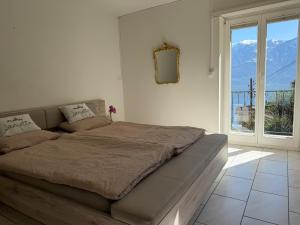 a bed in a white room with a large window at Molino Vecchio in Ronco sopra Ascona