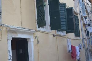a building with green shuttered windows and a door at Lemonia apartment Old Town in Corfu
